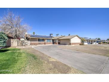 Charming single-story home featuring a long driveway, solar panels, and tidy landscaping at 3210 W Belmont Ave, Phoenix, AZ 85051