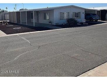 Exterior view of manufactured home featuring a covered porch, well-kept landscaping, and paved driveway at 3330 E Main St # 323, Mesa, AZ 85213