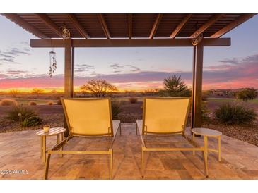 Inviting outdoor patio featuring lounge chairs under a pergola overlooking a sunset and golf course at 3942 N San Marin Dr, Florence, AZ 85132