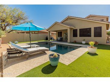 Backyard pool with lounge chairs and blue umbrella at 39526 N White Tail Ln, Anthem, AZ 85086