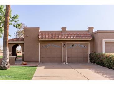 This home features a charming brown two-car garage with decorative windows and a red tile roof at 9837 E Michigan Ave, Sun Lakes, AZ 85248