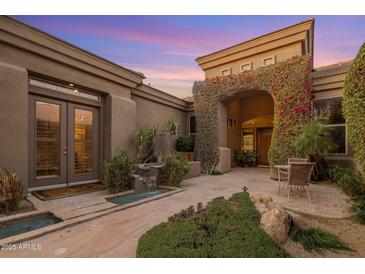 Stunning front entrance features a stone path, beautiful flowers, and elegant architecture at 10886 E Ludlow Dr, Scottsdale, AZ 85255