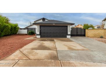 Two car garage with a black garage door and extra wide driveway with an iron gate at 18829 N 15Th Pl, Phoenix, AZ 85024