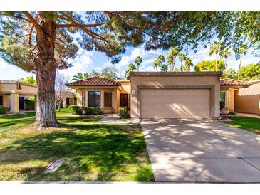 Charming single-story home featuring a well-manicured lawn and two-car garage and mature landscaping at 19220 N 93Rd Ave, Peoria, AZ 85382