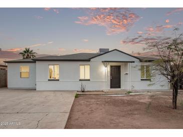 Charming single-story home with white brick, black trim, and desert landscaping at dusk at 3035 W Pierce St, Phoenix, AZ 85009