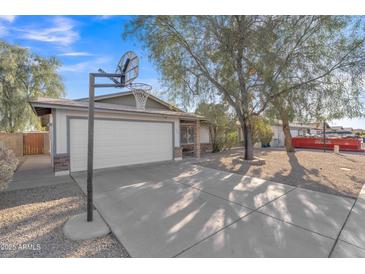 Traditional-style home featuring a two-car garage, basketball hoop, and desert landscaping at 3349 E Carmel Ave, Mesa, AZ 85204