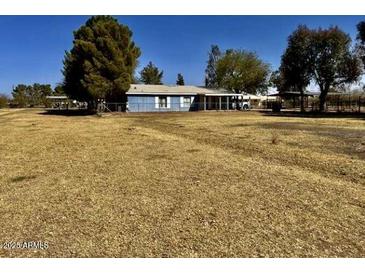 A single-story blue home with a spacious yard is perfect for peaceful, country living at 5078 E Rolling Ridge Rd, San Tan Valley, AZ 85140