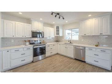 Bright kitchen features white cabinets, stainless steel appliances, and tile backsplash at 6808 W Sierra St, Peoria, AZ 85345