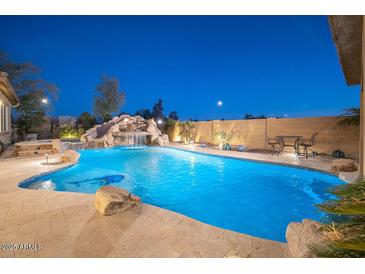 Backyard pool area with stone features, slide, waterfall, and lush landscaping at 7157 E Ivyglen Cir, Mesa, AZ 85207