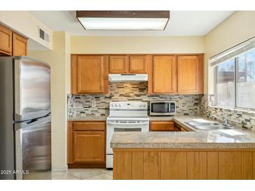 Traditional kitchen features wood cabinets, tile backsplash, and stainless steel refrigerator at 931 W Hermosa Dr, Tempe, AZ 85282