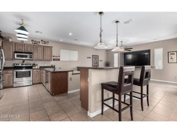 Open-concept kitchen with stainless steel appliances, bar seating, and ample counter space at 17574 W Gelding Dr, Surprise, AZ 85388