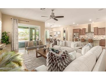 This open-concept living room features neutral tones, a ceiling fan, and sliding glass doors leading to the outdoor patio at 20584 W Hillcrest Blvd, Buckeye, AZ 85396