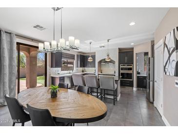 Open concept kitchen featuring gray cabinets, a large center island with barstool seating, and modern pendant lighting at 2423 W Bramble Berry Ln, Phoenix, AZ 85085