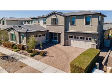 A charming two-story home with a brick driveway and two-car garage, enhanced by beautiful landscaping at 9960 E Strobe Ave, Mesa, AZ 85212