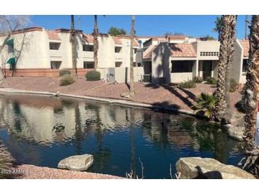 Waterfront condominium complex with red tile roofs, lush landscaping, and palm trees at 12221 W Bell Rd # 119, Surprise, AZ 85378