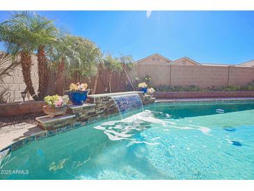 Inviting backyard pool with a beautiful waterfall feature and desert landscaping at 16763 W Adams St, Goodyear, AZ 85338