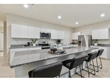 Spacious kitchen with granite countertops, stainless steel appliances, and a large center island with seating at 35961 W San Ildefanso Ave, Maricopa, AZ 85138