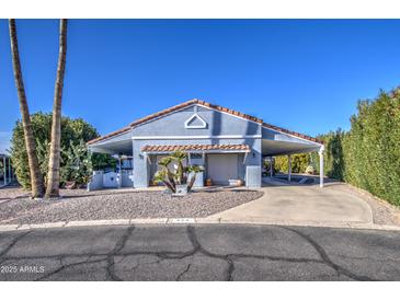 Charming blue home with a well-manicured desert landscape and covered carport at 654 S 83Rd Way, Mesa, AZ 85208