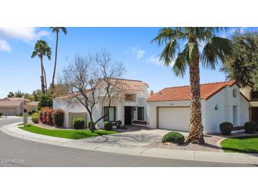Inviting desert home with a red tile roof, green lawn, palm trees, and a circular driveway at 10076 E Calle De Cielo E Cir, Scottsdale, AZ 85258