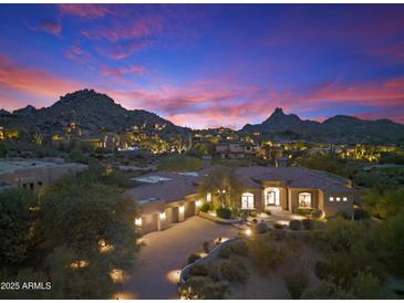 Stunning desert home featuring beautiful stone driveway, three-car garage and mountain views at sunset at 10379 E White Feather Ln, Scottsdale, AZ 85262