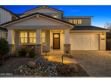 Charming two-story home featuring a well-manicured yard, stone accents, and a welcoming front porch in the evening light at 11172 N San Clemente St, Surprise, AZ 85388