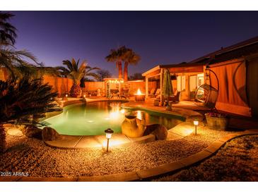 Serene backyard pool area with lush tropical landscaping and a cozy fire pit under the covered patio at 11182 S Hopi Dr, Goodyear, AZ 85338