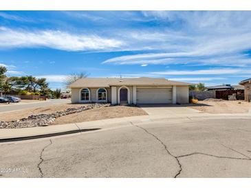 Charming single-story home featuring desert landscaping, arched windows, and a two-car garage under a bright, partly cloudy sky at 16638 N Landis Ln, Glendale, AZ 85306