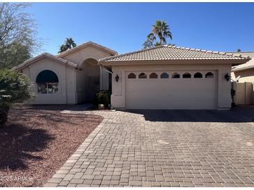Attractive single-story home featuring a two car garage and a desert landscaped front yard at 26242 S Thistle Ln, Sun Lakes, AZ 85248