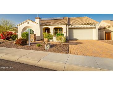 Charming single-story home featuring a tile roof, desert landscaping, and a brick paver driveway at 18322 W Thistle Landing Dr, Goodyear, AZ 85338