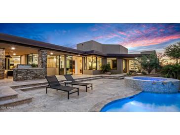 Beautiful backyard featuring a luxurious pool, hot tub, and outdoor seating under a colorful sunset sky at 39877 N 107Th Way, Scottsdale, AZ 85262