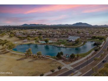 Beautiful aerial view showcasing the community lake, pool, and clubhouse with mountain views at 4769 E Thunderheart Trl # 101, Gilbert, AZ 85297