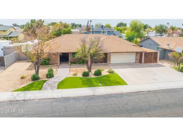 Charming single-story home featuring a manicured front yard, a two-car garage, and a welcoming walkway at 6409 W Riviera Dr, Glendale, AZ 85304