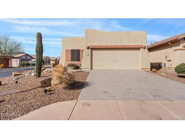 Tan single-story home featuring desert landscaping, a two-car garage and mature Saguaro cactus at 10718 E Secret Canyon Rd, Gold Canyon, AZ 85118