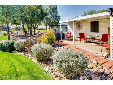 Charming home exterior with landscaped yard, red brick path, and covered patio area with seating at 17200 W Bell Rd # 2221, Surprise, AZ 85374