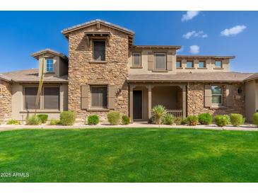 Charming two-story home featuring a stone facade, covered porch, and a well-maintained green lawn at 18519 N 94Th St, Scottsdale, AZ 85255