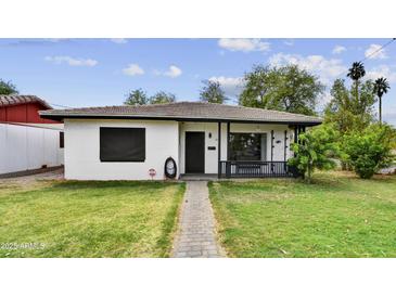 Charming single story home features a well-manicured lawn and a brick walkway, complemented by lush trees at 2045 W Orange Dr, Phoenix, AZ 85015