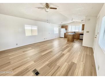 Bright living room open to kitchen featuring wood-look flooring, ceiling fan, and large windows at 318 S Crismon Rd # 83, Mesa, AZ 85208