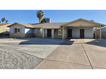 Charming single-story home featuring light blue paint, covered carport, desert landscaping, and a spacious driveway at 4231 E Roeser Rd, Phoenix, AZ 85040