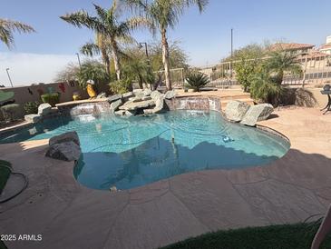 Inviting swimming pool with rock features and lush landscaping for a backyard oasis at 6026 E Vermillion Cir, Mesa, AZ 85215