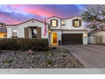 Charming two-story home featuring a red tile roof, stone landscaping, and a three-car garage at 9544 E Theia Dr, Mesa, AZ 85212