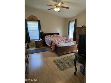 Cozy main bedroom with a ceiling fan, natural light, and an ensuite bathroom at 17821 N Woodrose Ave, Surprise, AZ 85374
