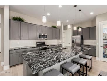 This kitchen features a large granite island, gray cabinets, stainless steel appliances, and wood flooring at 1936 W Kinfield Trl, Phoenix, AZ 85085