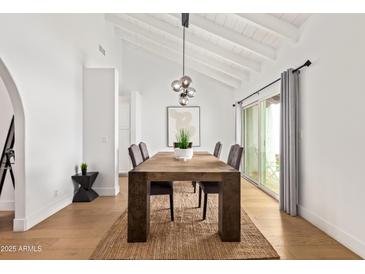 Bright dining room featuring a wooden table, modern lighting, and sliding doors to outdoor area at 2629 S Country Club Way, Tempe, AZ 85282