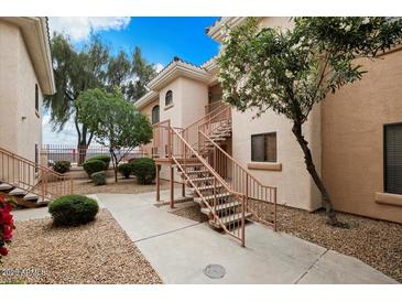 Inviting condo exterior featuring well-maintained landscaping and stairs leading to upper levels at 10030 W Indian School Rd # 203, Phoenix, AZ 85037