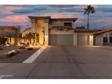 Charming two-story home featuring a spacious three-car garage and well-maintained landscaping at dusk at 826 W Royal Palms Dr, Gilbert, AZ 85233