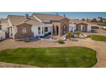 Elegant home featuring a stone facade, decorative fountain, manicured lawn, and desert landscaping at 11225 E Starflower Ct, Chandler, AZ 85249