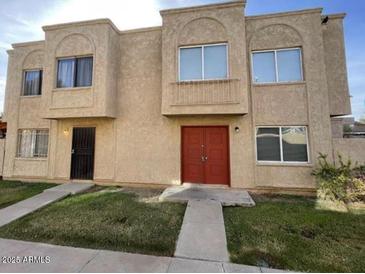 Two-story home featuring a stucco facade, red double-door entry, and well-maintained front lawn at 4258 N 68Th Ln, Phoenix, AZ 85033