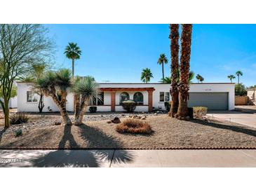 Charming single-story home featuring desert landscaping and a front porch with arched accents at 6729 E Sharon Dr, Scottsdale, AZ 85254