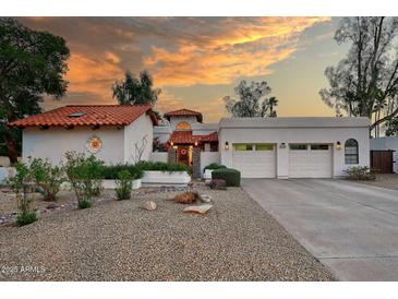 Stunning home with a three-car garage, desert landscaping, and a red-tile roof at sunset at 8717 E Spanish Barb Trl, Scottsdale, AZ 85258