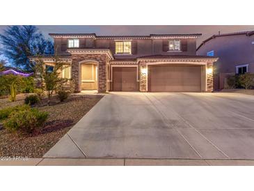 Charming two-story home with a stone-accented facade and a spacious three-car garage at twilight at 3840 W Brogan Ct, New River, AZ 85087